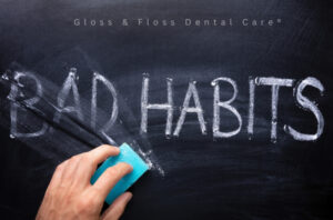 Hand suddar ut texten "Bad Habits" på en svart tavla – symbol för att bryta dåliga tandvanor och förbättra munhälsan.