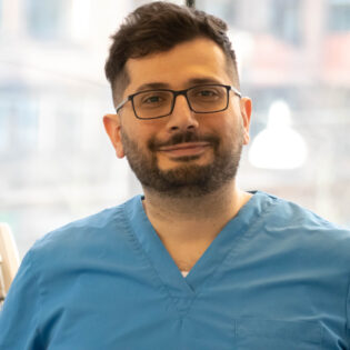 Hussein, kallad Hosse, tandhygienist på Gloss & Floss i Stockholm, i blå arbetskläder på kliniken.